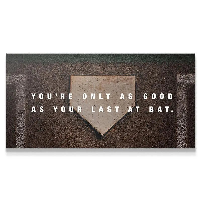 Overhead view of the worn home plate featuring the 'Last At Bat' motivational quote centered on the dirt.