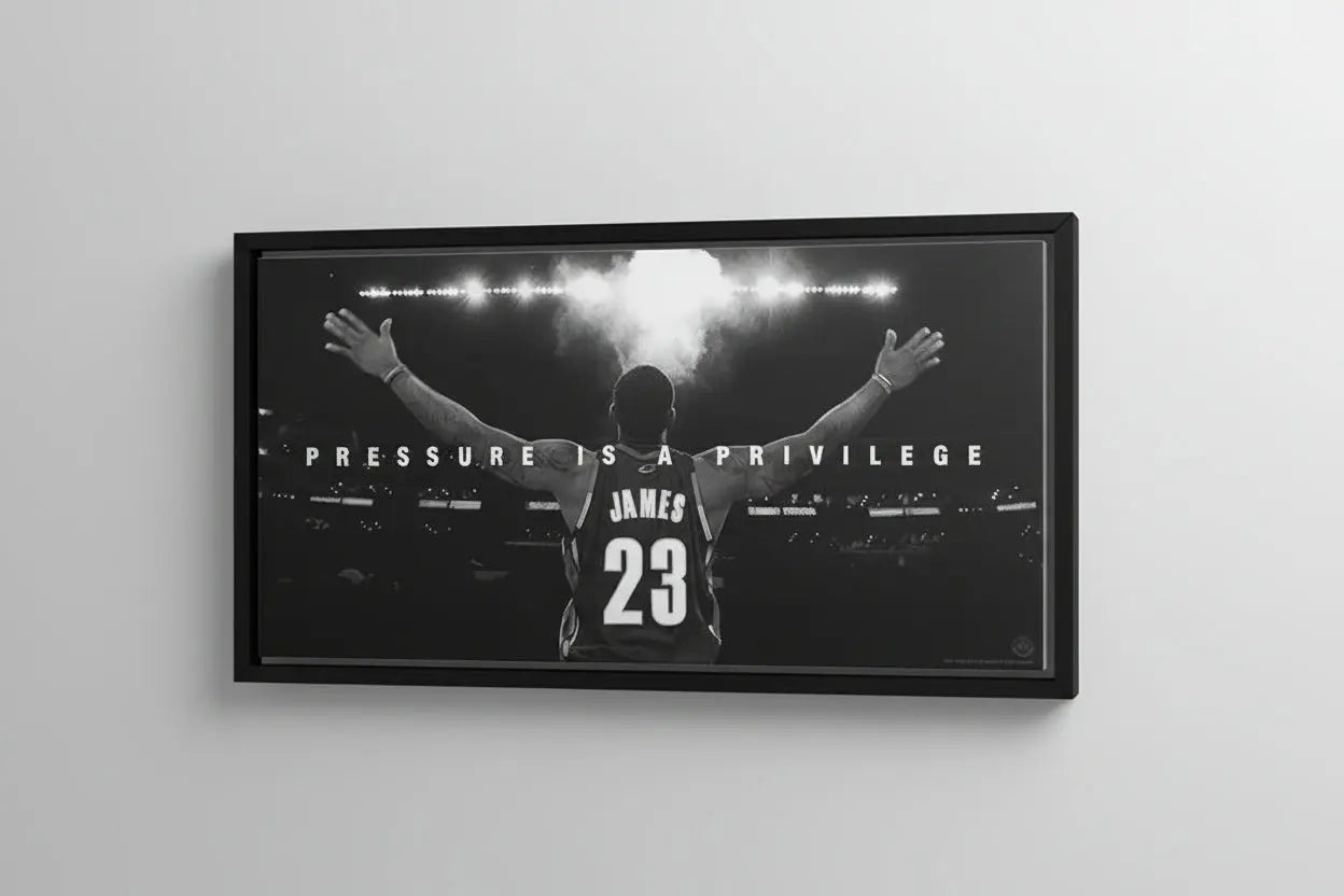 Framed poster of a basketball player with 'Pressure is a Privilege' text on a gray wall.