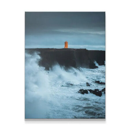 Full view of the dramatic coastal Lighthouse standing firm against huge ocean waves.