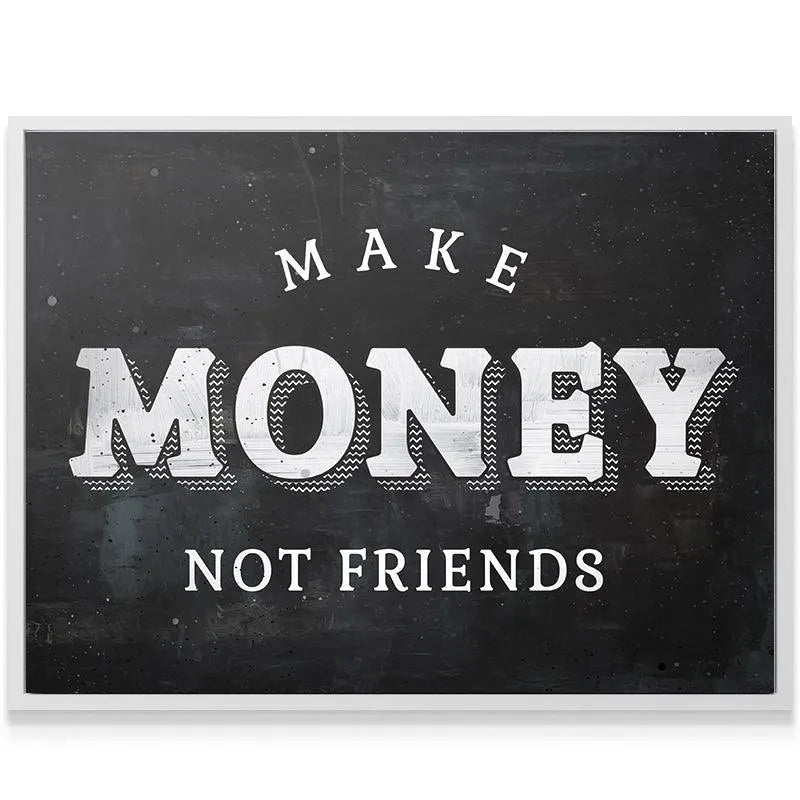 Angled shot of the motivational chalkboard art 'Make Money Not Friends' hanging above a modern minimalist desk setup.