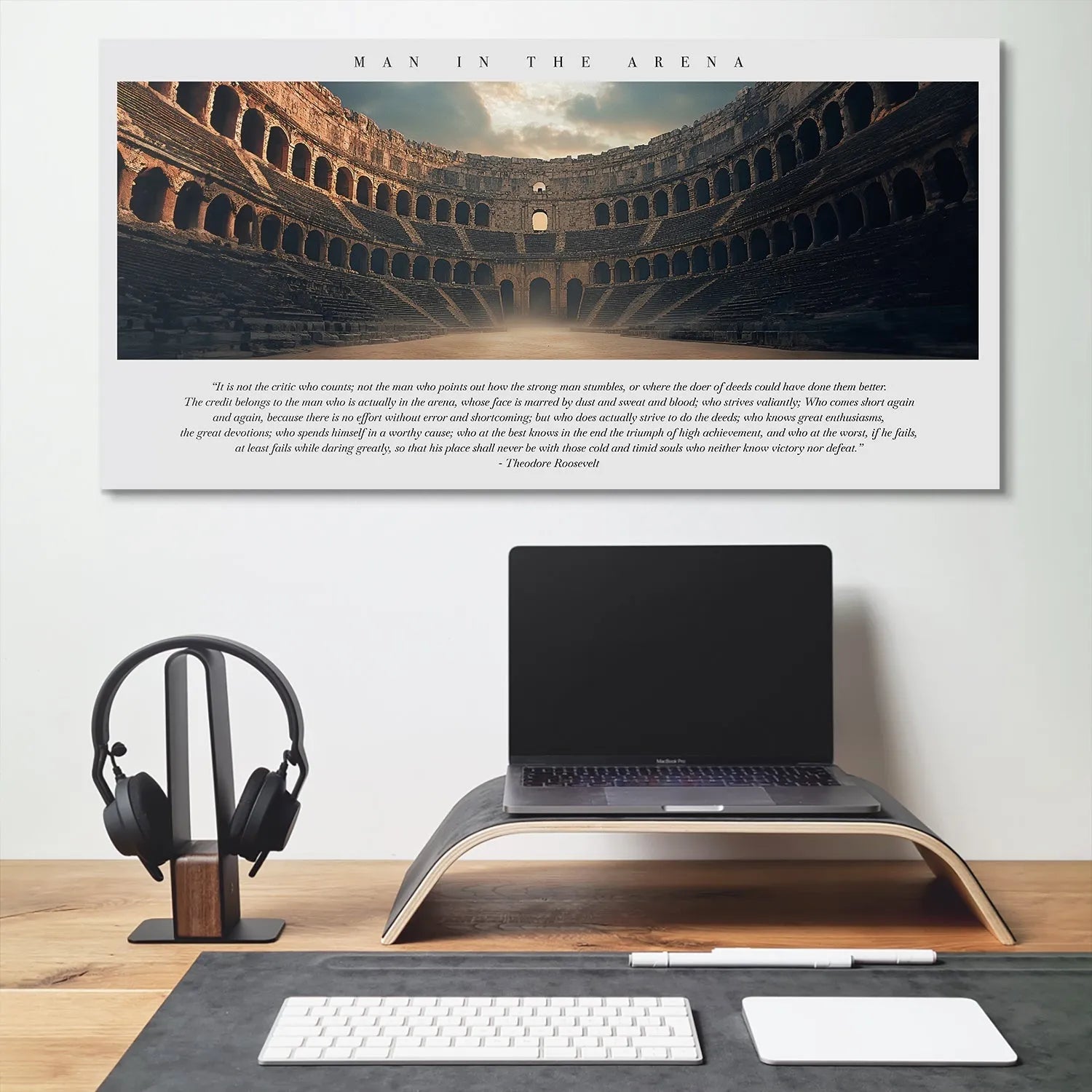 Lifestyle shot of the 'Man In The Arena' print mounted above a desk in a modern executive office setting.