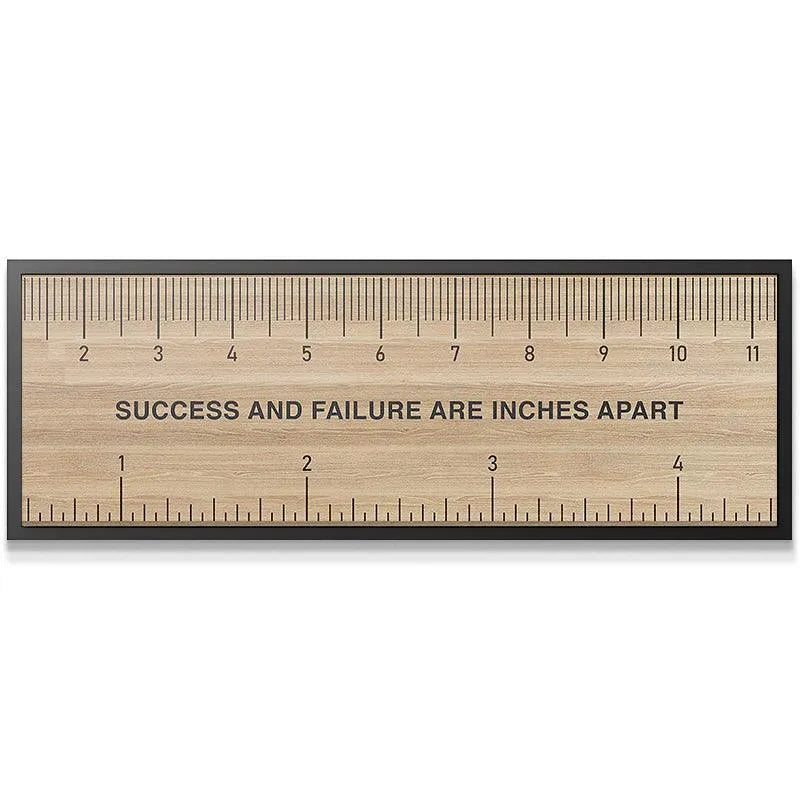 Close-up detail shot of the quote 'SUCCESS AND FAILURE ARE INCHES APART' engraved on the 'Measure Of Success'.