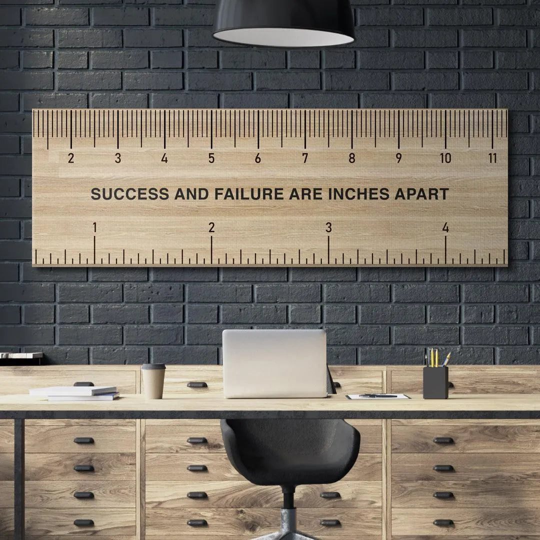 Lifestyle shot of the 'Measure Of Success' ruler resting on a desk next to a notebook and pencil for context.