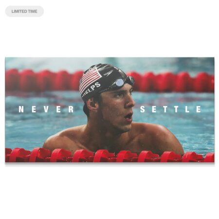 Close-up of Michael Phelps' determined expression in the pool, captioned 'Never Settle'.