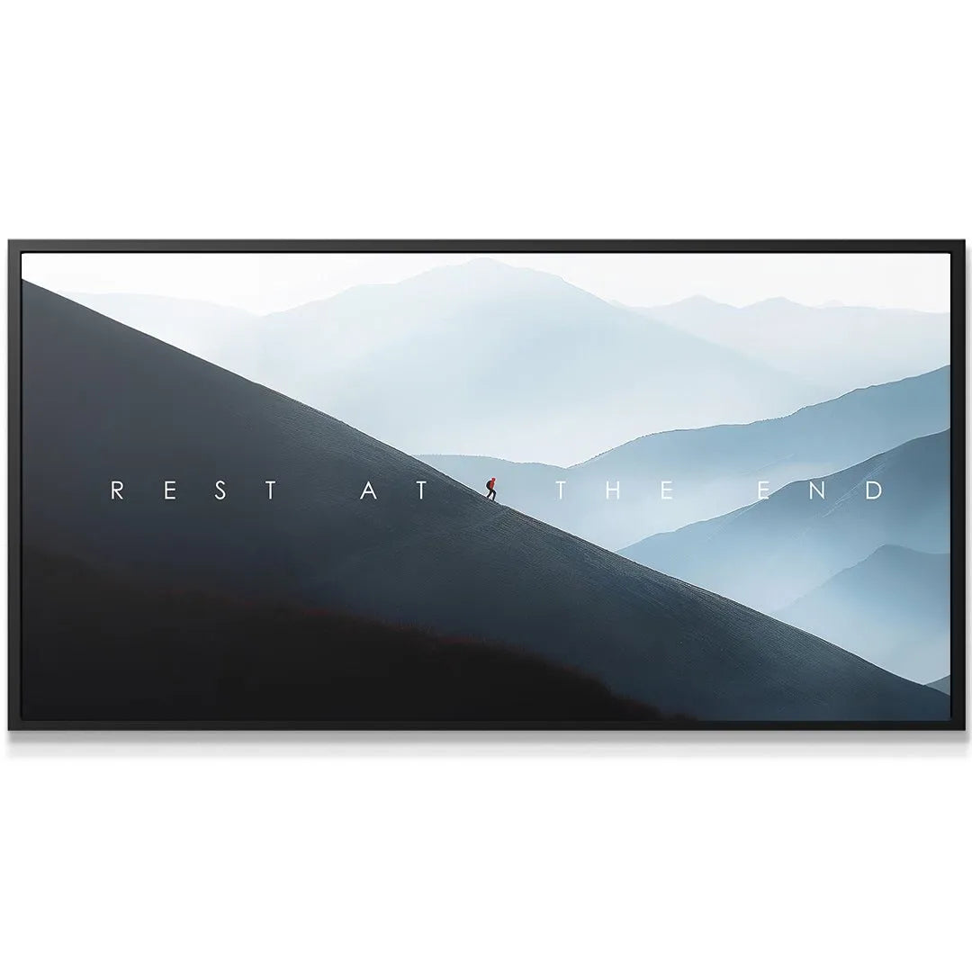 Minimalist wall decor featuring misty blue mountain layers and the inspirational quote 'Rest At The End'.