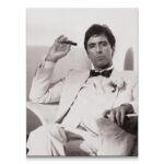 Full black and white studio portrait of Scarface - White Tux sitting down, holding a cigar.