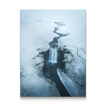 Aerial view of Skogafoss waterfall surrounded by frozen, snow-covered Icelandic tundra.
