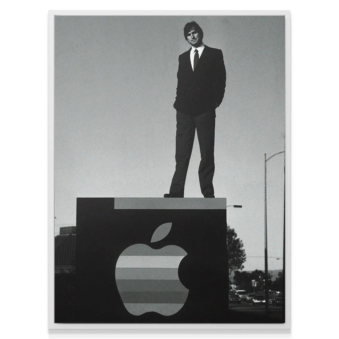 Low-angle view emphasizing the scale of the Apple sign and Jobs 'Standing On Business' against the sky.