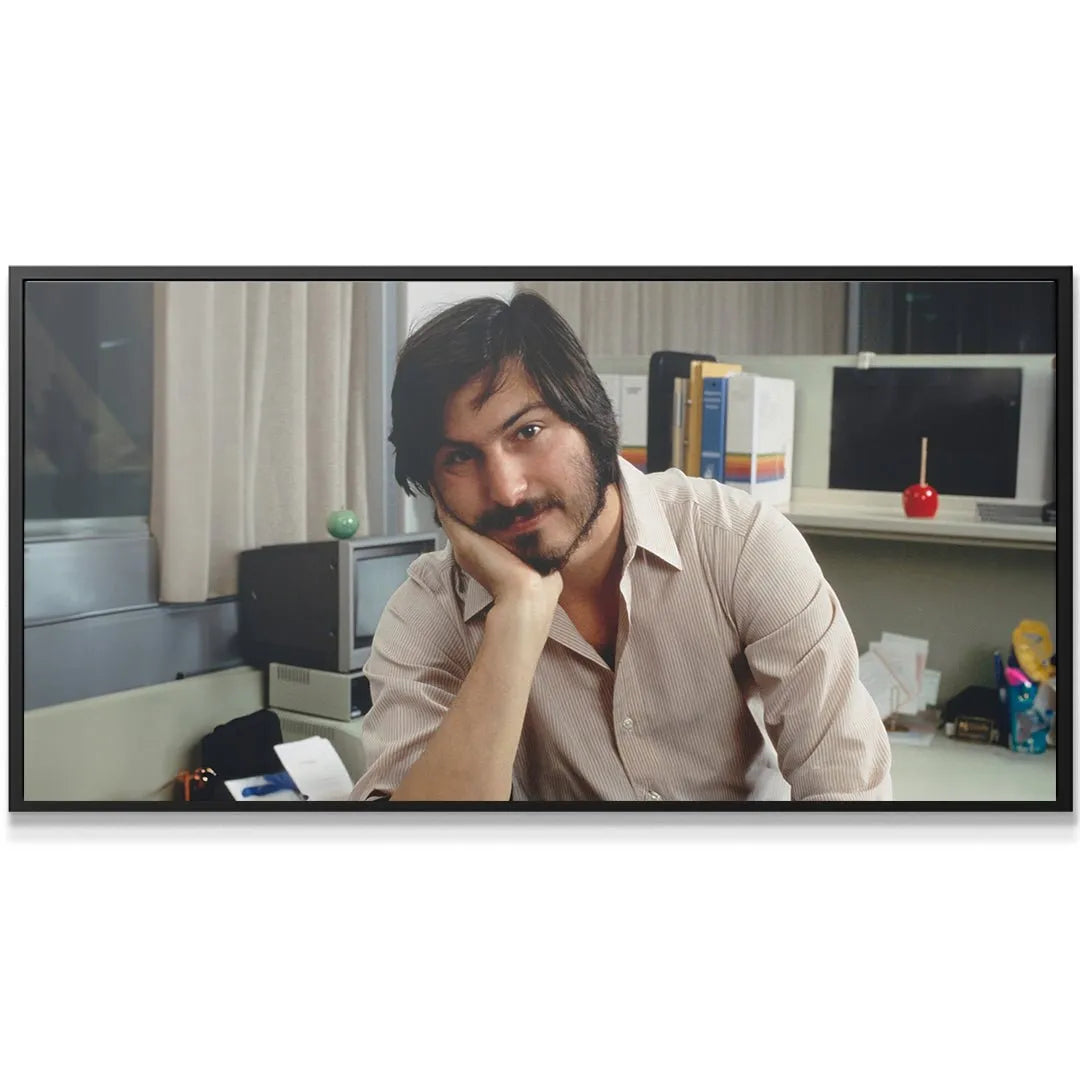 Wide shot of Steve Jobs leaning on his hand at a cluttered desk, featuring the 'Stay Hungry Stay Foolish (No Quote)' title.