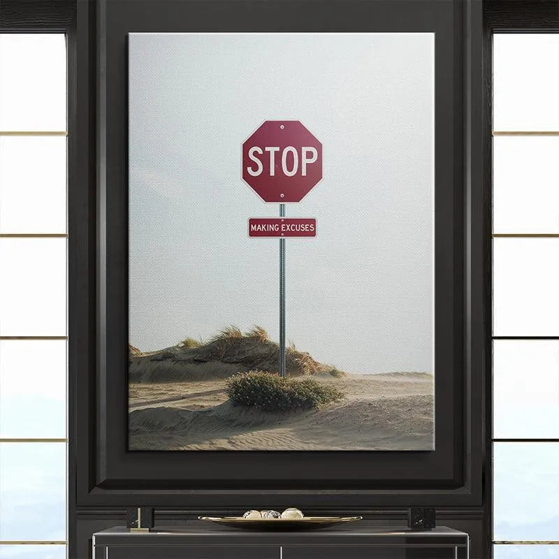 Wide-angle environmental view of sand dunes and minimal greenery framing the custom sign telling viewers to 'Stop Making Excuses'.