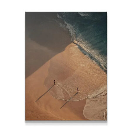 Aerial view of Strangers or Friends figures standing at the ocean's edge during sunset.