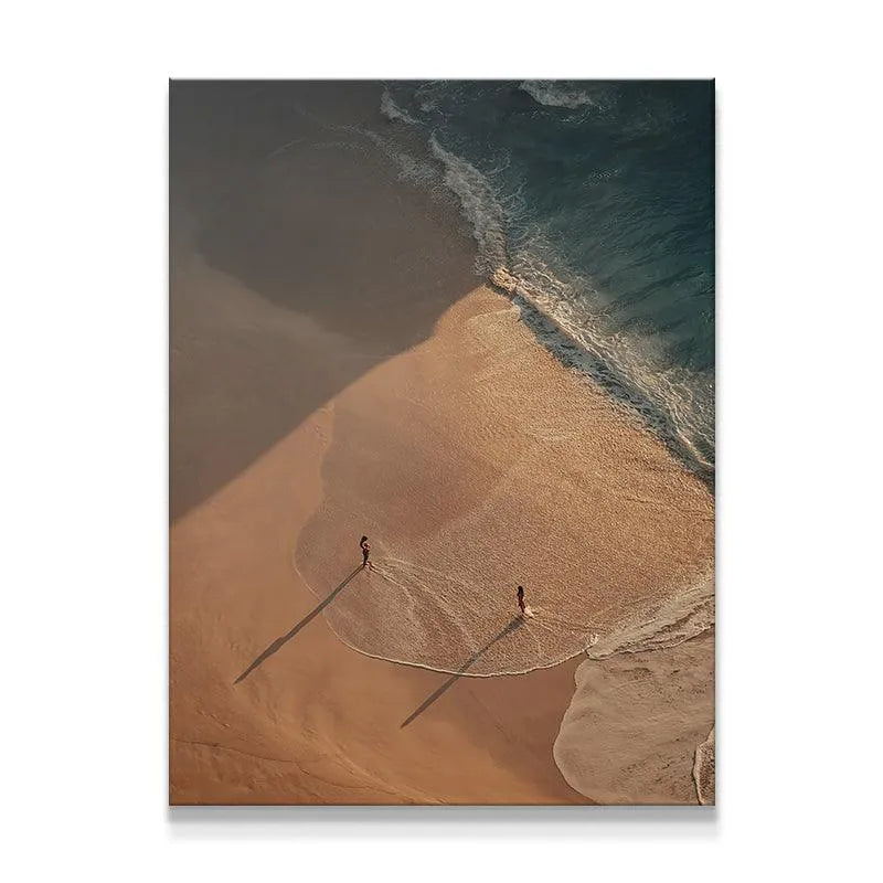 Aerial view of Strangers or Friends figures standing at the ocean's edge during sunset.