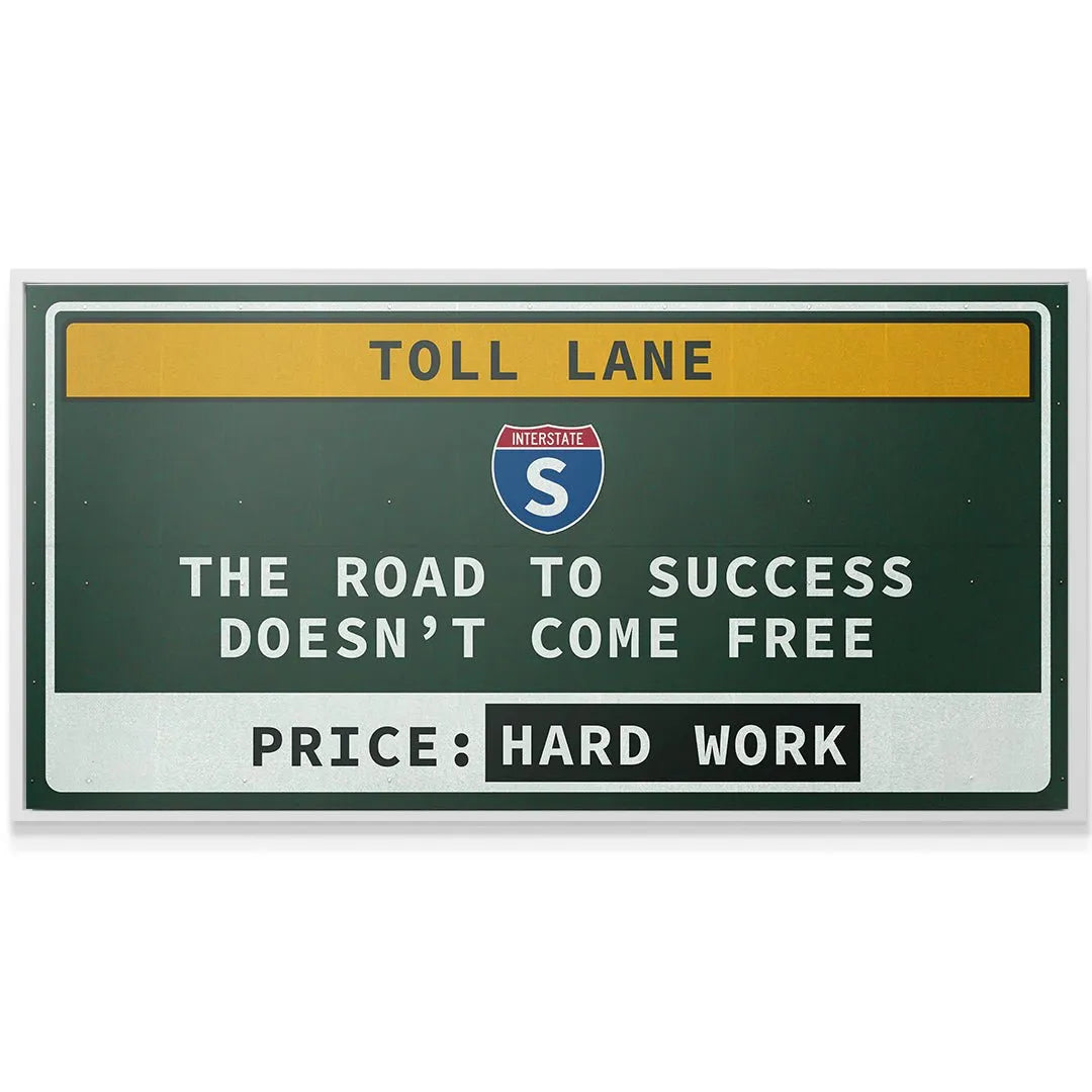 Lifestyle shot of the 'Toll Lane' sign mounted above an entrepreneur's desk in a modern office.